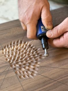 a man is using a drill to cut wood with a circular pattern on the floor