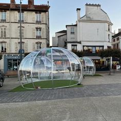 there is a glass house in the middle of the street with grass growing inside it