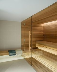 a wooden sauna in a bathroom with glass walls