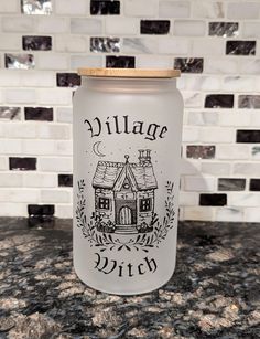 a glass jar with the words village witch on it sitting on a marble countertop