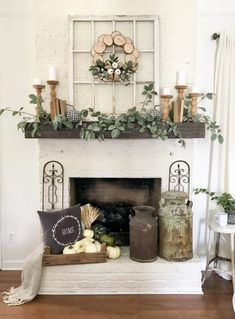 a fireplace with candles, pumpkins and greenery on the mantel above it