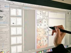 a person is drawing on the screen of a computer monitor with a pen in their hand