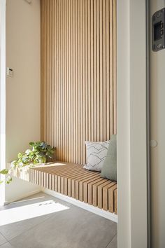 a wooden bench sitting in front of a window next to a plant on top of a potted plant