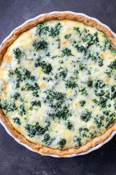 a quiche with spinach and cheese in a pie pan on a table top