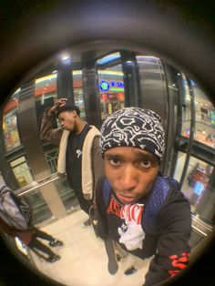 a man in a beanie looking at the camera through a fish - eye lens