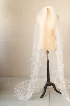 a mannequin with a veil on top of it sitting on a wooden stand