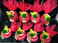 a group of pink and green items on a black surface with red flowers in the background