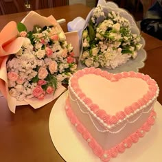 two heart shaped cakes sitting on top of a table next to bouquets of flowers