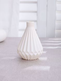 a white vase sitting on top of a table