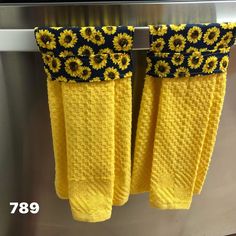 two yellow towels hanging on a towel rack in front of a stainless steel oven door