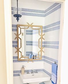 a bathroom with blue and white tiles on the walls, sink and mirror in it