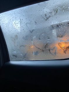 rain is falling on the windshield of a car as it sits in front of a window