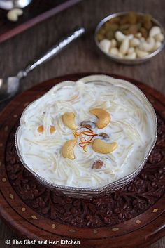 a bowl filled with food sitting on top of a wooden table next to spoons