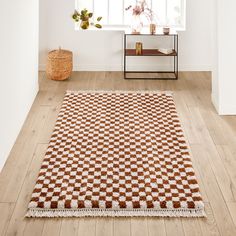 a brown and white rug sitting on top of a wooden floor next to a window