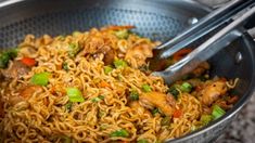 a bowl filled with noodles and vegetables on top of a table