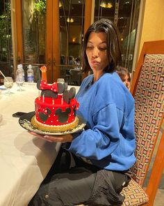 a woman sitting at a table with a mickey mouse cake