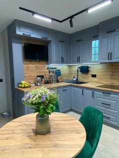 a kitchen with blue cabinets and green chairs around a round wooden table in the center