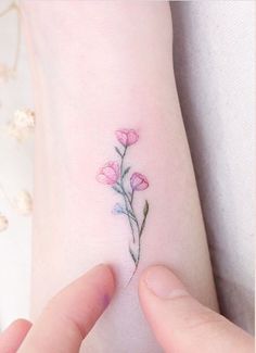 a small pink flower tattoo on the wrist