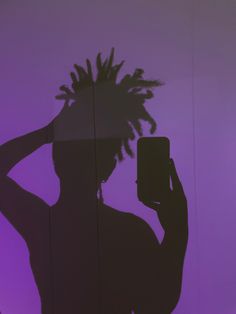 a person with dreadlocks holding a cell phone in front of a purple background