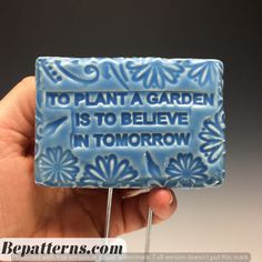 a hand holding a lollipop that says to plant a garden is to believe in tomorrow