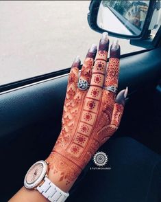 a woman's hand with henna on it sitting in the driver's seat