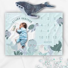 a baby laying on top of a blue blanket next to a clock and sea animals