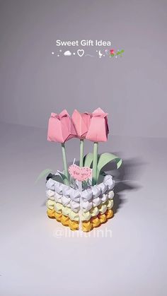 two pink flowers are in a vase filled with small marshmallows and candy