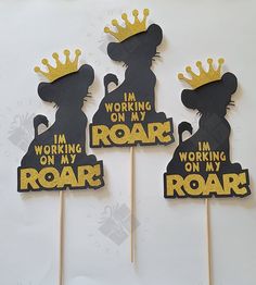 three black and gold cupcake toppers with the words roar on them, in front of a white background