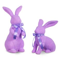 two purple stuffed animals sitting next to each other in front of a white background and one has a ribbon on it's head