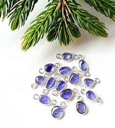 a bunch of blue beads sitting on top of a table next to a pine tree