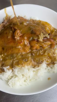 a white plate topped with rice and meat covered in gravy