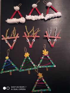 christmas tree ornaments made out of construction paper on a black surface with clouds in the background