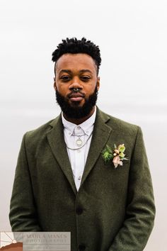 a man in a green suit and flower boutonniere