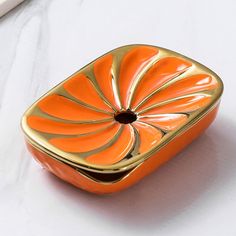 an orange and gold square shaped object on a white surface