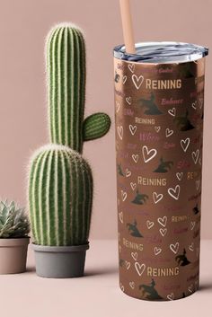 a cactus next to a tumbler with the words reining on it and hearts