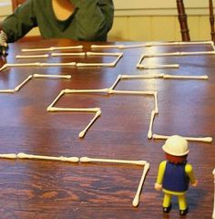 a woman sitting at a wooden table with toy figures in front of the board game