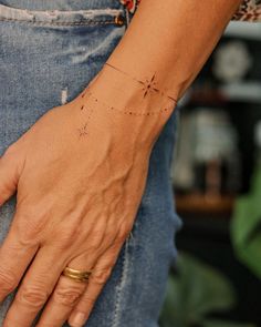 a person's hand with a cross tattoo on their left wrist and gold ring