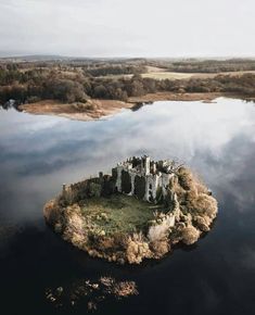 an island with a castle on it in the middle of a lake surrounded by trees