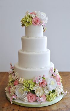 a three tiered white wedding cake with pink and green flowers