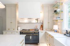 a kitchen with white cabinets and gold trimmings on the stove top, counter tops, and shelves