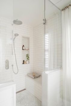 a white tiled bathroom with a shower, sink and bathtub in the corner is shown