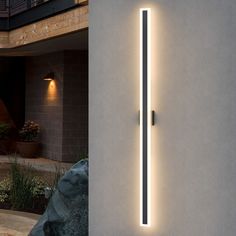 a wall mounted light on the side of a building next to a stone planter