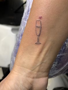 a woman's arm with a tattoo that has a wine glass and heart on it