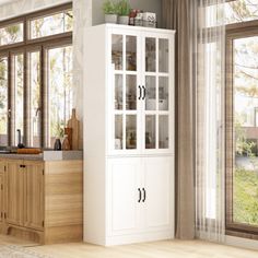 a kitchen with white cabinets and wood flooring next to large open windows on the wall