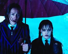 two people are standing under an umbrella in the rain and one person is wearing a tie