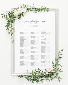 a wedding seating chart with flowers and greenery on the side, in white frame