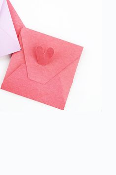 an open envelope with a heart cut out of it sitting on top of a white surface