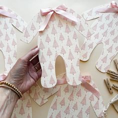 a person is cutting out some paper shapes with scissors and pink ribbon on the table