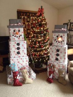 two snowmen made out of boxes next to a christmas tree