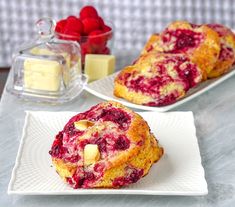 two white plates topped with raspberry muffins and sliced strawberries on a table